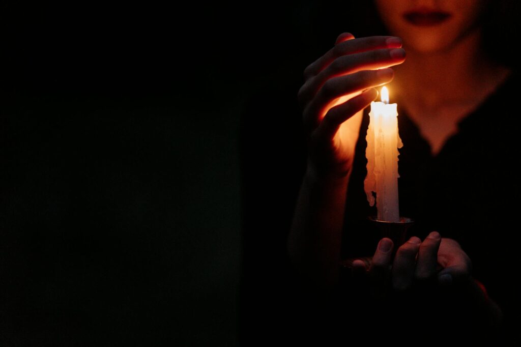 a person covering the lighted candle he is holding